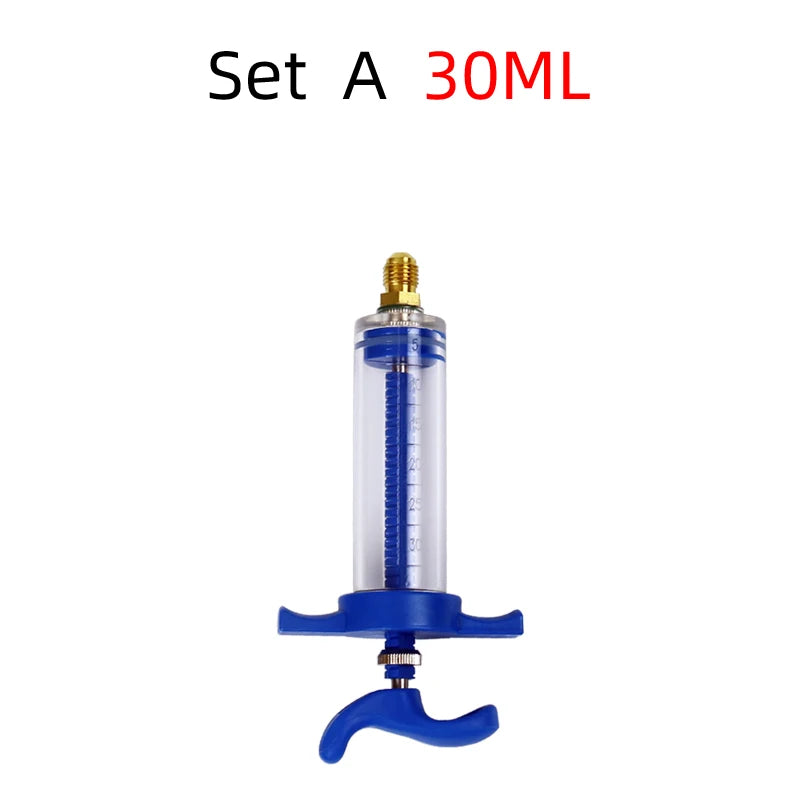 A clear glass syringe injector with a gold tip and blue plunger for air conditioning oil and dye.