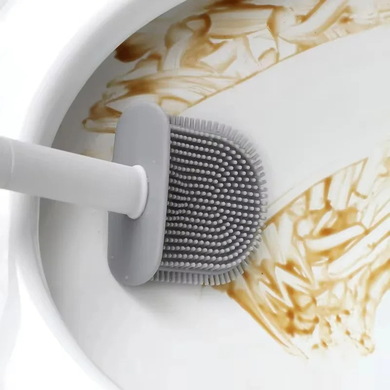 A white wall-mounted toilet brush set with a silicone head is shown cleaning a white porcelain surface.