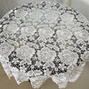 White lace tablecloth with embroidered rose pattern covering a round table.