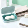 A light blue transparent soap dish with a drainage tray and a lid is shown on a white surface.