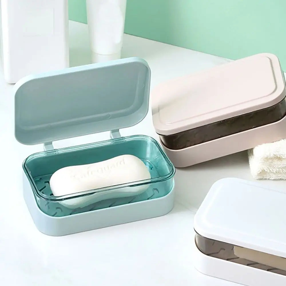 A light blue transparent soap dish with a drainage tray and a lid is shown on a white surface.