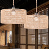 Two large woven paper rope pendant lampshades hang in a wooden interior setting.