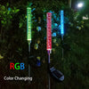 Three vertical LED lights with RGB color changing capabilities illuminating a garden path.
