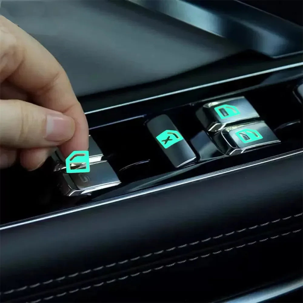 A hand is interacting with a car window switch featuring glow-in-the-dark stickers.