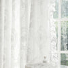 White sheer curtain with delicate lace embroidery filtering light through a window.