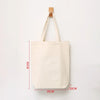 A plain off-white canvas shopping tote bag hanging from a wooden peg.