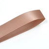 A roll of double face satin ribbon in a dusty rose color shown diagonally.