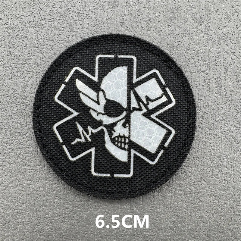 A round black patch featuring a white medical cross design with an eye motif.