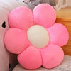 A pink lifelike sunflower plush pillow with soft furry texture resting on a light-colored surface.