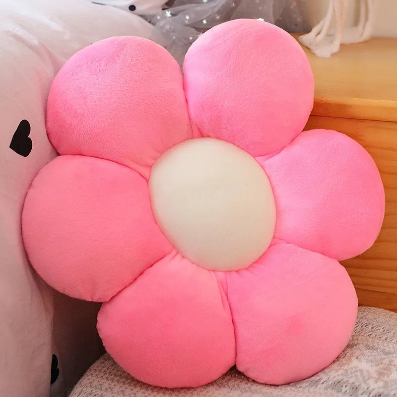 A pink lifelike sunflower plush pillow with soft furry texture resting on a light-colored surface.