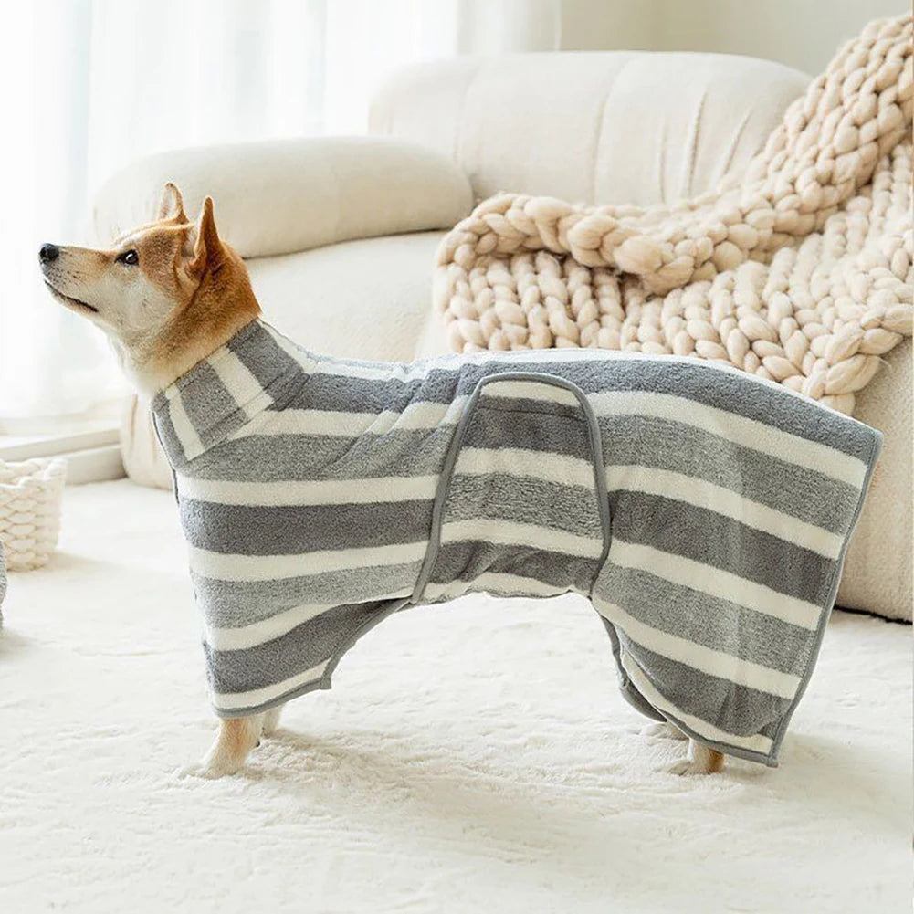 A dog wearing a gray and white striped quick-dry ultra-absorbent bathrobe lies on a white rug next to a sofa.