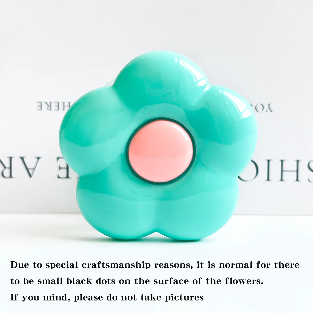 A light blue flower-shaped phone grip stand with small black dots on the surface.