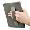 A hand is holding a dark olive green e-reader case with a strap for protection.