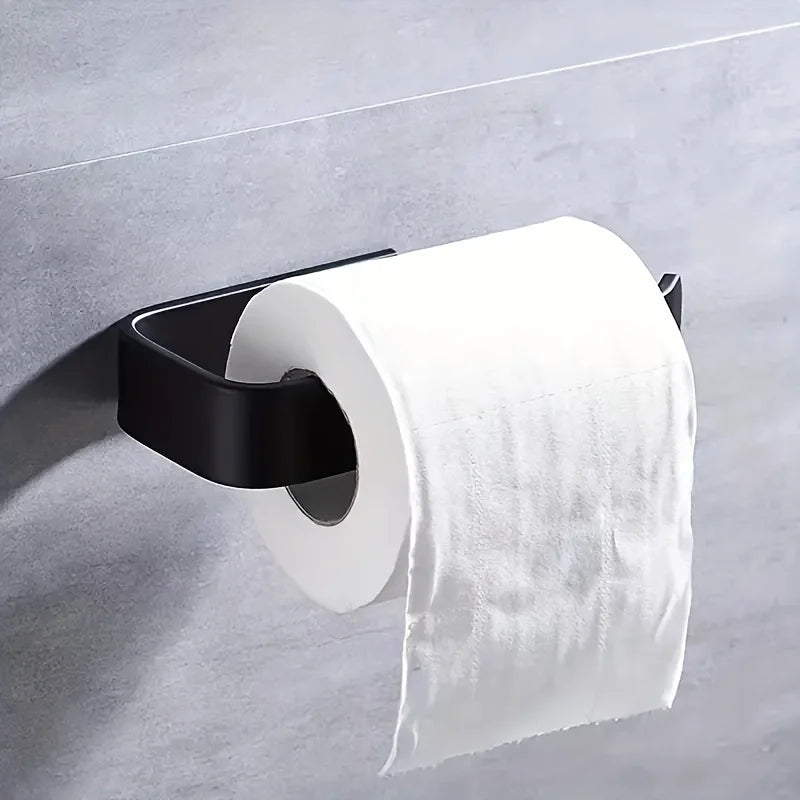 A white roll of toilet paper is mounted on a black holder against a gray wall.