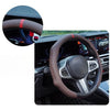 Close-up view of a perforated leather steering wheel cover with red stitching on a car interior.