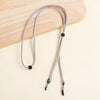A gray adjustable lanyard for glasses is displayed on a light wooden surface.