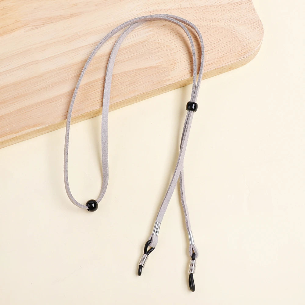 A gray adjustable lanyard for glasses is displayed on a light wooden surface.