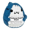 A blue and white crocheted shark figurine with closed eyes and an inspirational card attached.