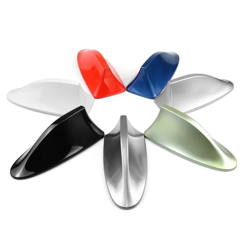 A collection of five colored shark fin car antennas, including red, blue, white, and silver, arranged in a circle.