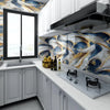Modern kitchen featuring white cabinetry, marble countertops, and blue and gold marbled wall tiles.