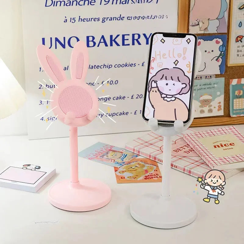 A pink rabbit mobile phone and tablet stand is displayed on a white surface next to a sign.