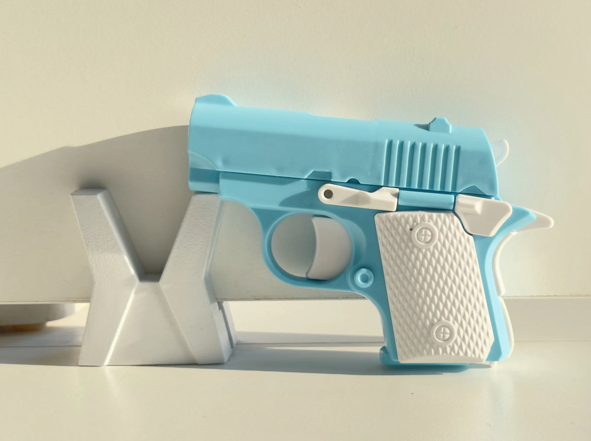 A light blue mini 3D printed gravity fidget pistol toy resting on a white surface.