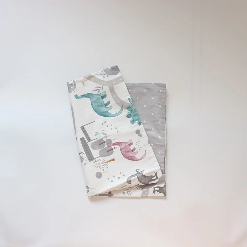 A stack of soft cotton baby pillowcases featuring watercolor cartoon animals in teal, pink, and gray.
