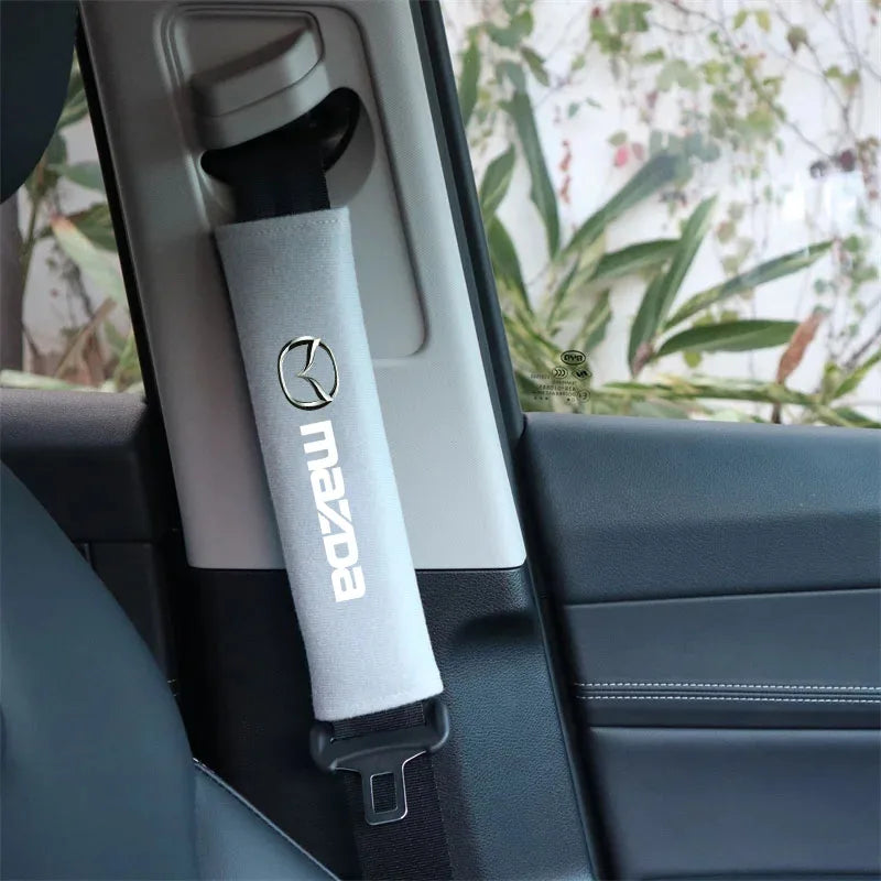 A gray soft cotton car seat belt shoulder protector cover is shown inside a car interior.