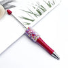 A close-up of a red ballpoint pen with a sparkly, multi-colored sequin tip resting on white paper.