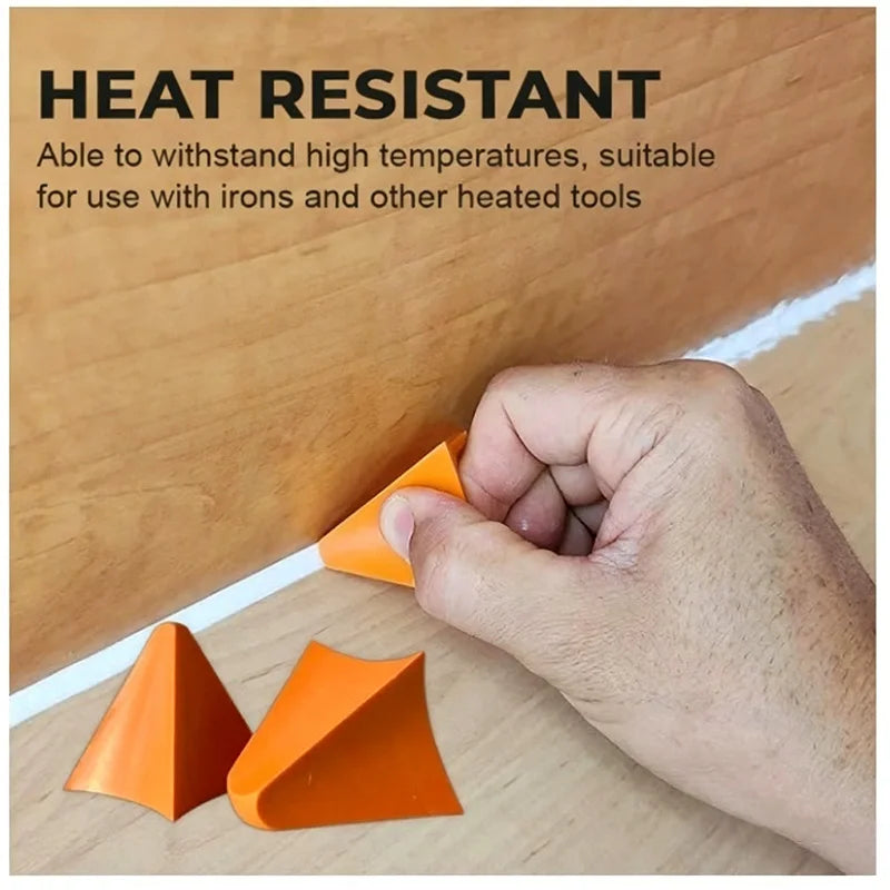 A hand holds an orange silicone tile grout filling tool against a wooden surface, demonstrating its heat resistance.