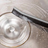 A close-up of a metal grout cleaning brush with black bristles resting on a circular metal cleaning disc.