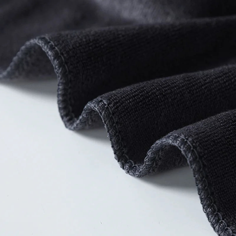 A close-up of a folded black microfiber bath towel showing its texture and soft drape.