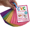 A hand holds a stack of colorful CVC words spelling flashcards, including cat and ram.