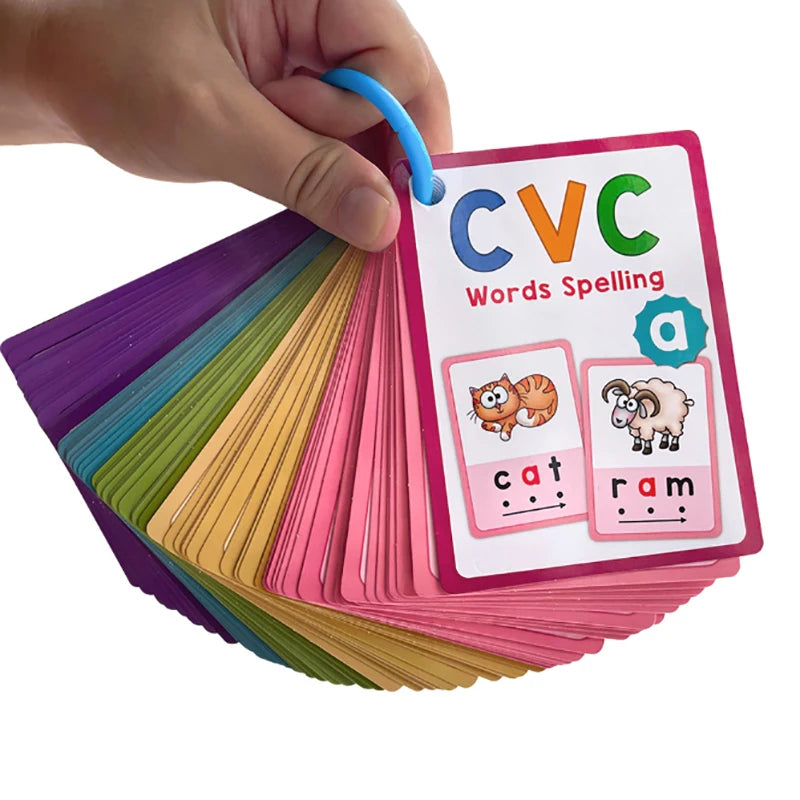 A hand holds a stack of colorful CVC words spelling flashcards, including cat and ram.