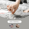 A hand is touching a fluffy gray shaggy area rug, highlighting its skin-friendly quality.