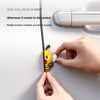 A hand is gently sticking a yellow 3D cartoon bee door edge protector onto a white surface.
