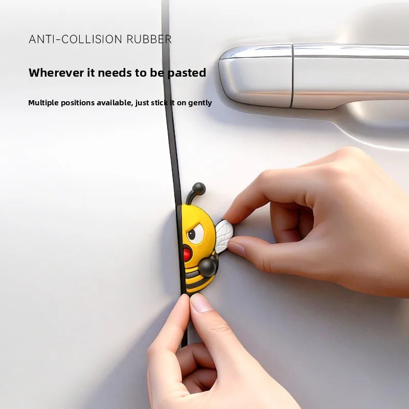 A hand is gently sticking a yellow 3D cartoon bee door edge protector onto a white surface.