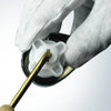 A hand wearing a white glove is operating a brass toilet tank flush lever with a side mount design.