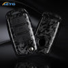 A pair of black carbon fiber car key covers for VW and Skoda models displayed on a dark surface.