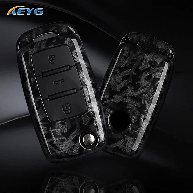 A pair of black carbon fiber car key covers for VW and Skoda models displayed on a dark surface.