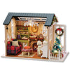 A wooden miniature dollhouse kit featuring a rustic interior, festive decorations, and an ornate chandelier.