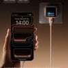 Une main tient un iPhone 17 Pro Max en charge via un chargeur dédié.
