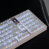 A close-up view of a white mechanical keyboard with blue backlit keys resting on a black surface.