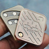 A hand holds a metal fidget slider toy with a skull design, showing its textured surface and sliding mechanism.