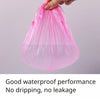 A hand is holding a pink disposable transparent waterproof shower cap bag.
