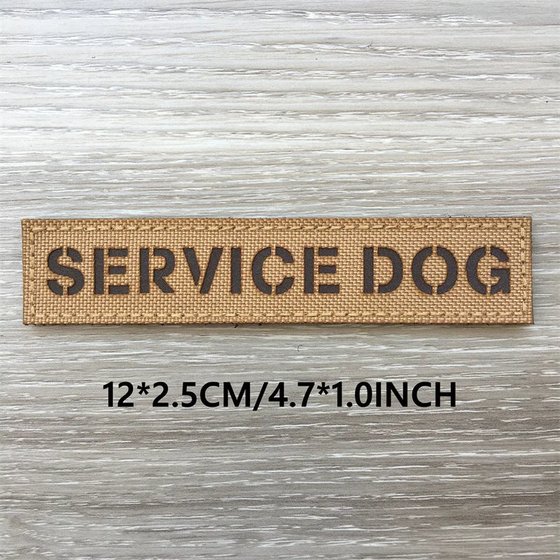 A brown woven patch with the text SERVICE DOG engraved on it, displayed on a light wooden surface.