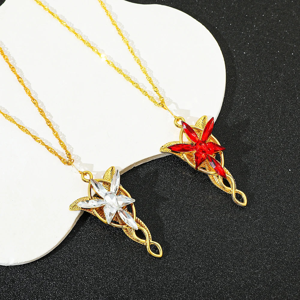 Gold crystal pendant necklace featuring a red gemstone and a clear star design on a white background.