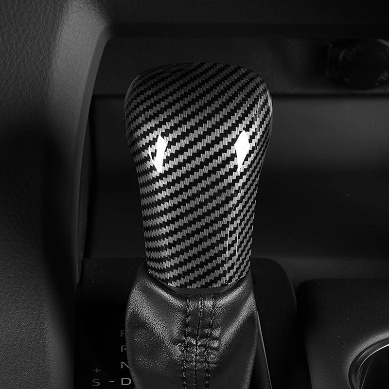 Close-up of a black carbon fiber gear shift knob cover for a Toyota Camry or Corolla.