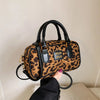 A brown and black leopard print retro hobo satchel bag with black leather handles and gold hardware.