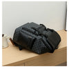 A black patterned PU leather backpack resting on a wooden surface.